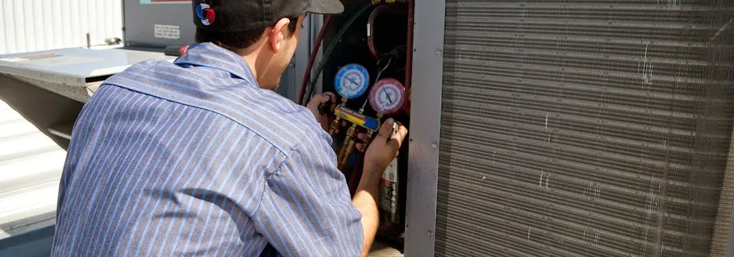 HVAC technician servicing a condenser unit in Carbondale